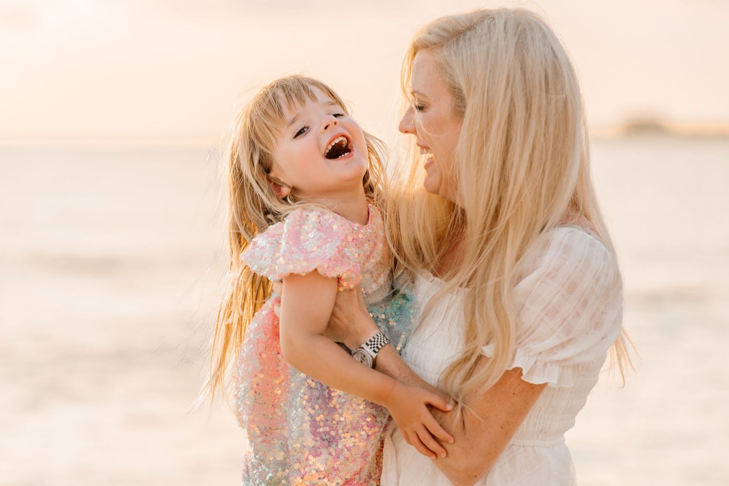 Joyful family embraces captured against a dreamy beach sunset backdrop.