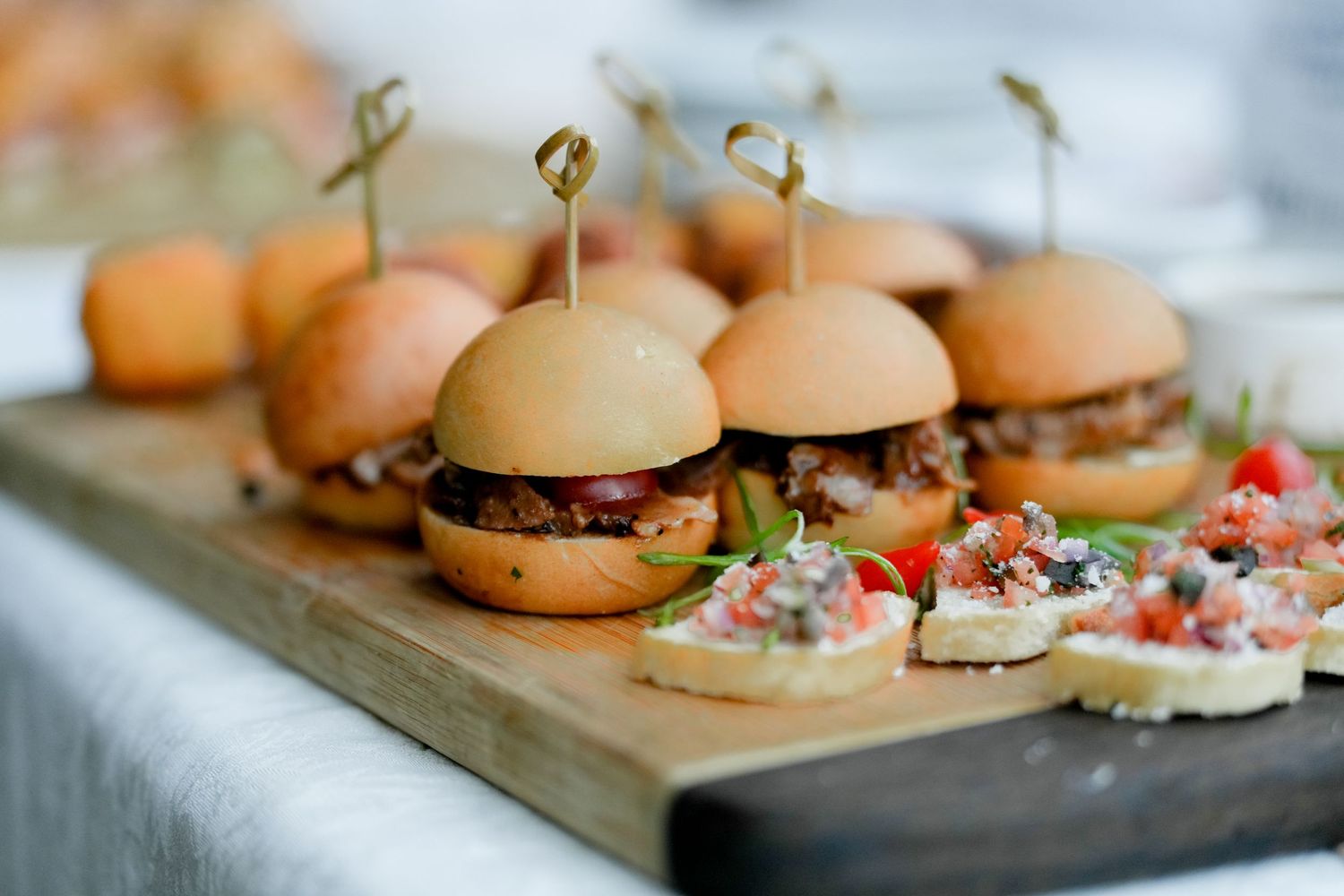 Array of gourmet sliders and appetizers displayed on wooden serving boards.
