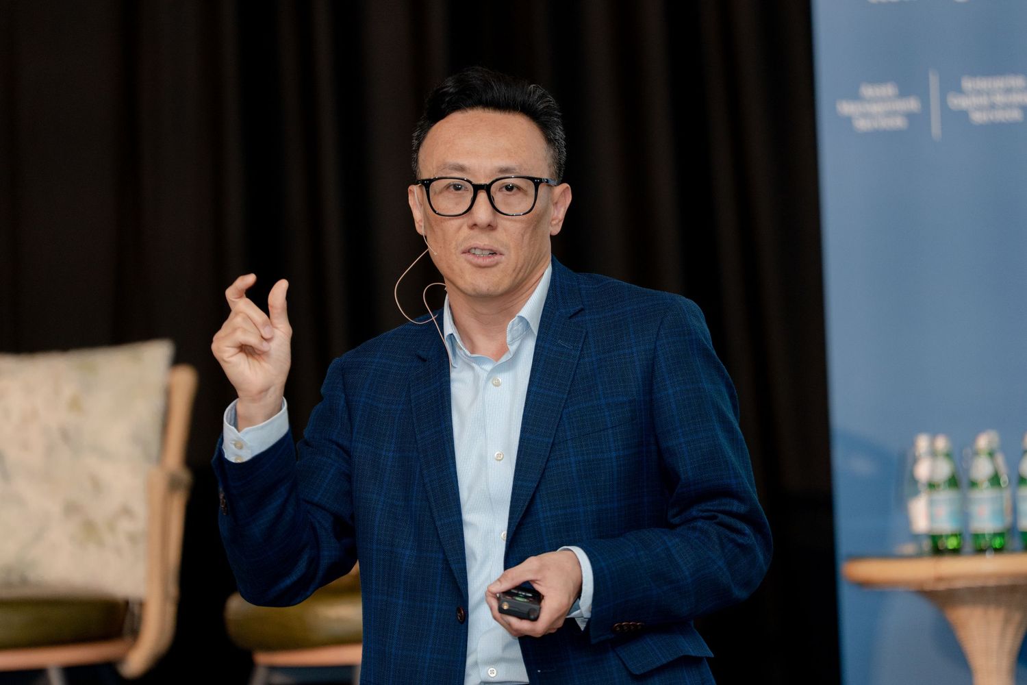 Professional speaker gesturing while giving a presentation at a corporate event.