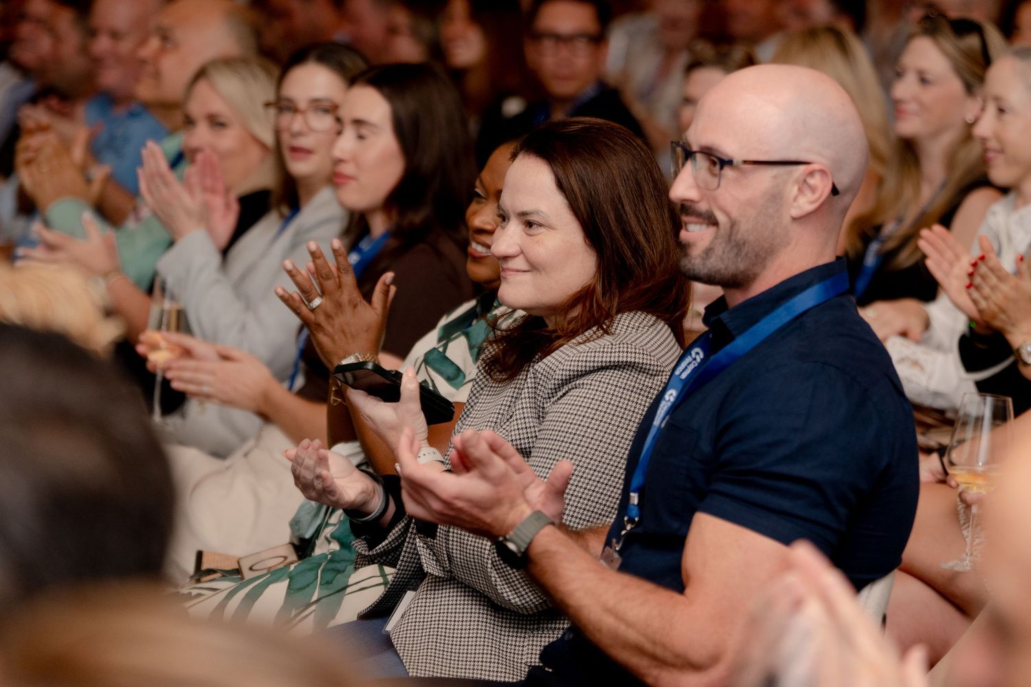 Engaged audience members applaud during professional conference session.