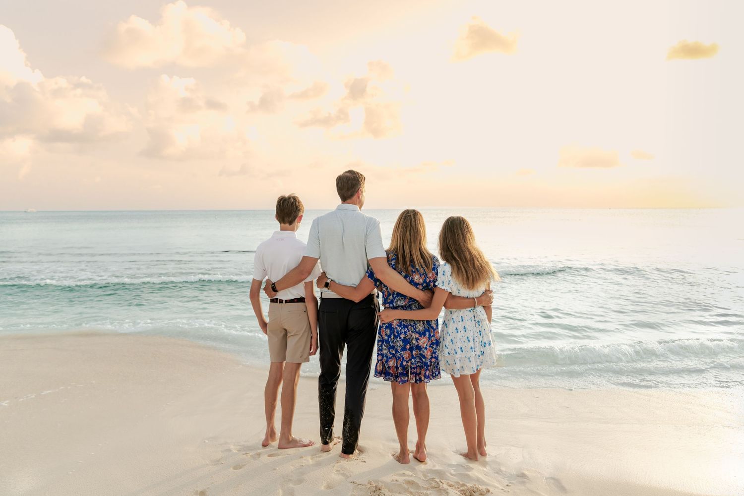 Family members walking together along shoreline during sunset beach photoshoot.