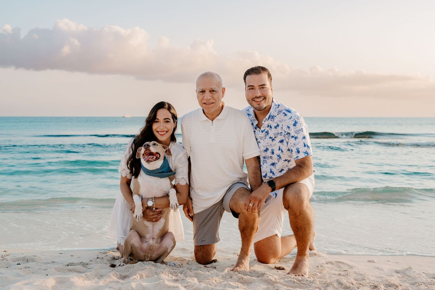 Sunset beach photography session with family posing on white sand near ocean waves.