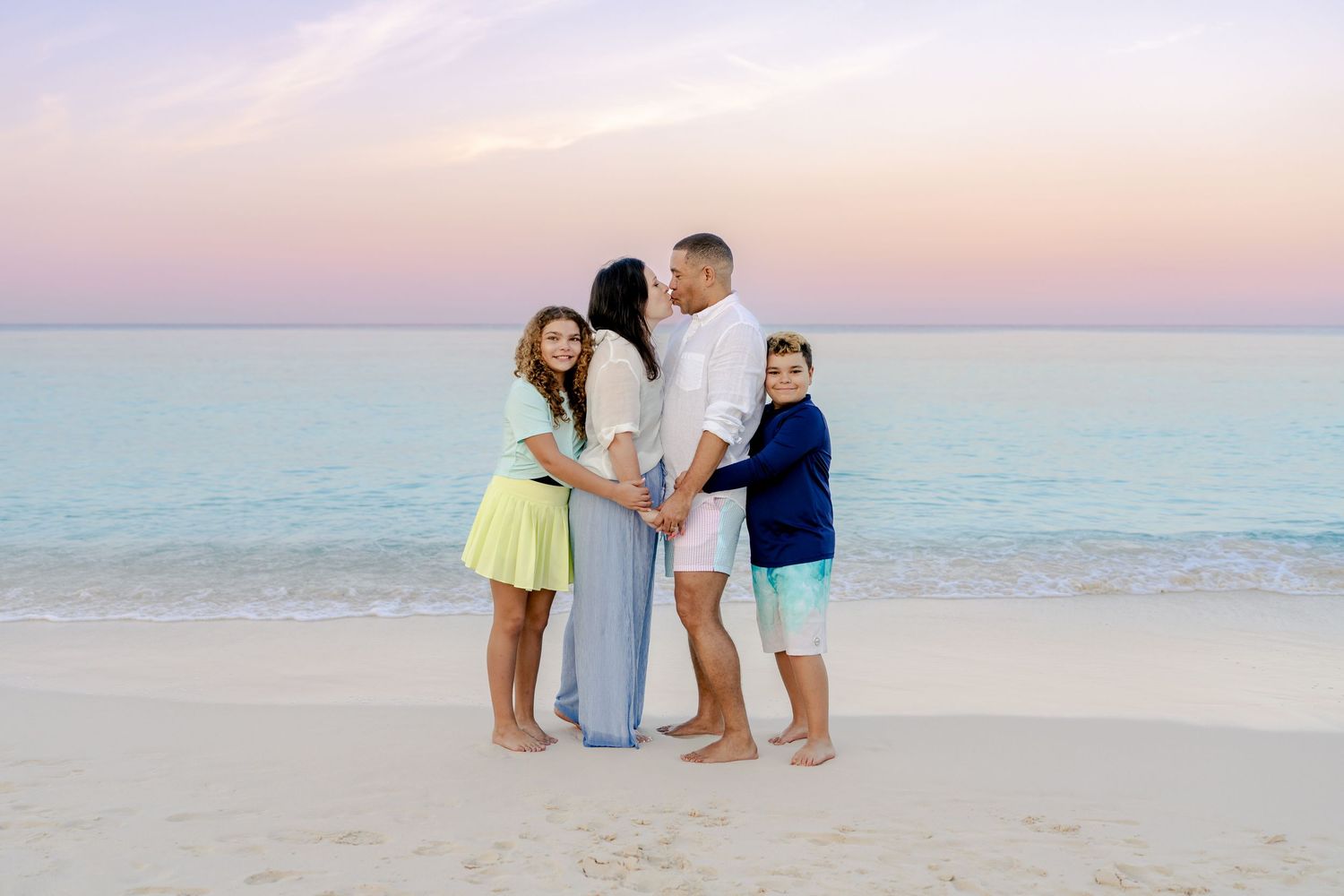 Candid beach photography session showing intimate family interactions at dusk.