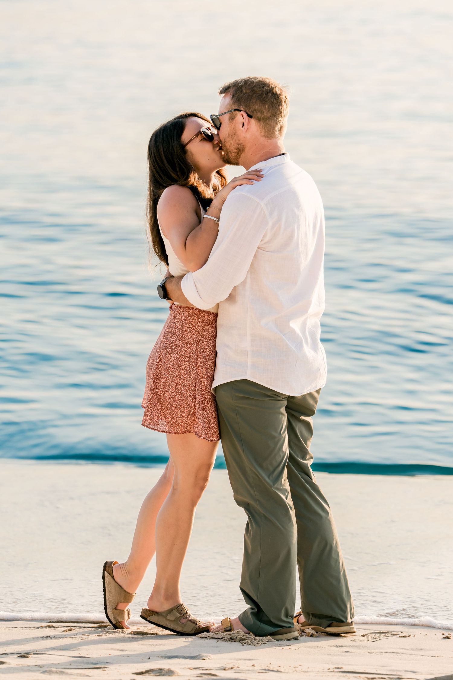 Couple sharing romantic moment on sandy beach at sunset.