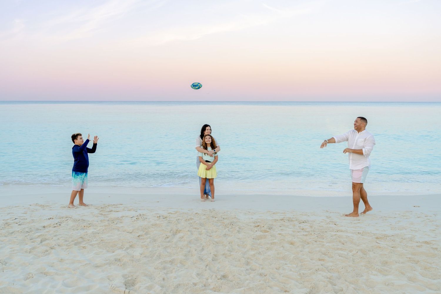 Playful beach photoshoot with family members running and playing in the sand.