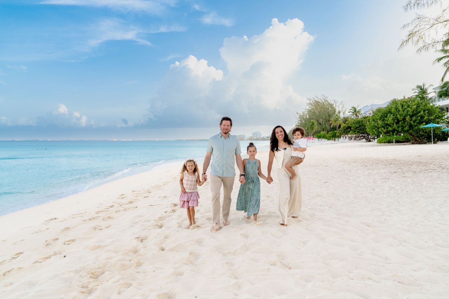 Extended family poses for photos on a tropical beach with crystal clear waters and blue skies.