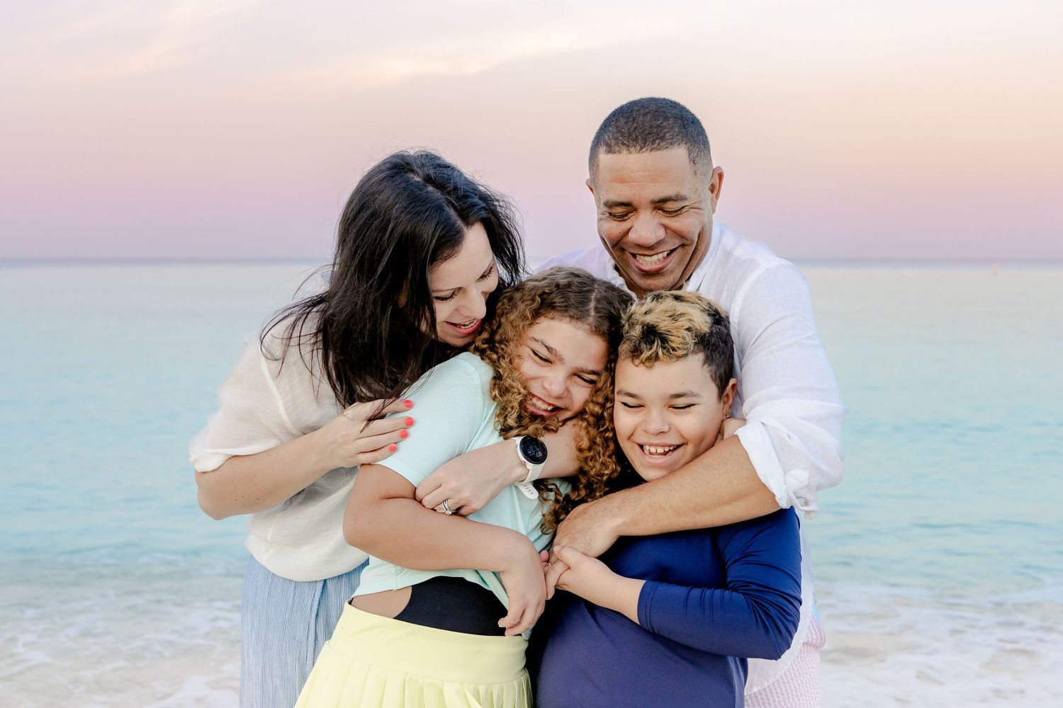 A loving family moment captured during sunset at a beautiful beach setting.