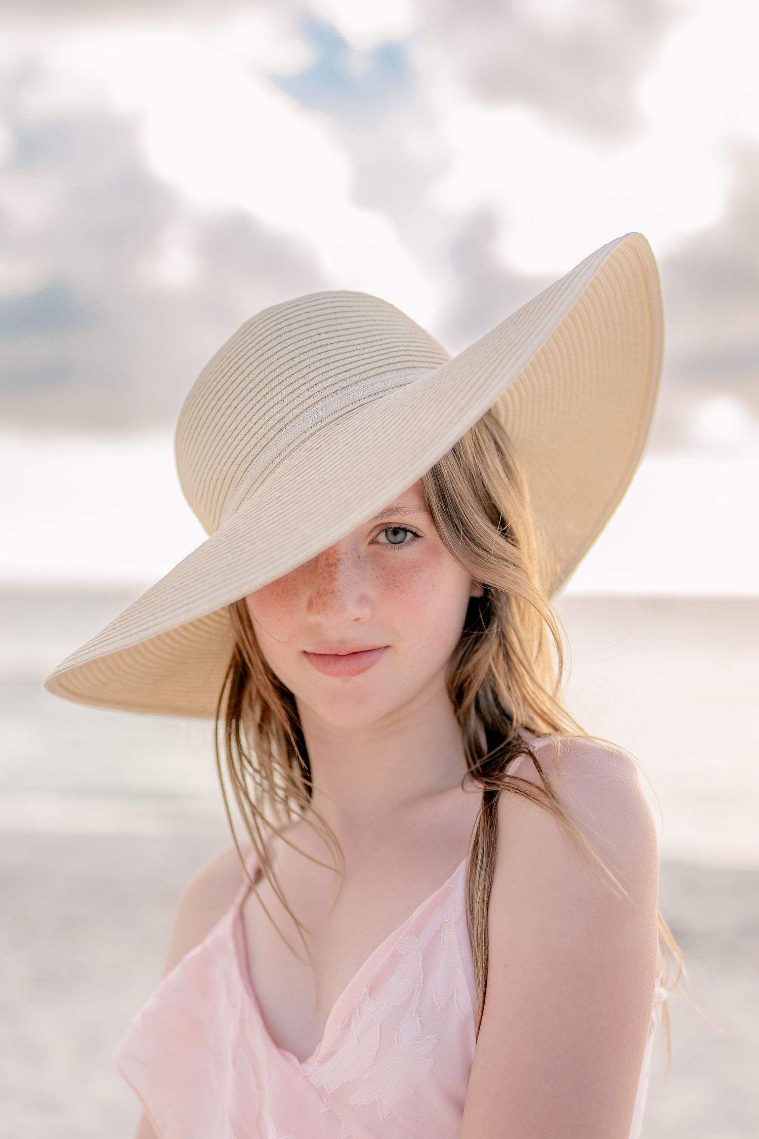 Woman in white sunhat relaxing on sunny beach.