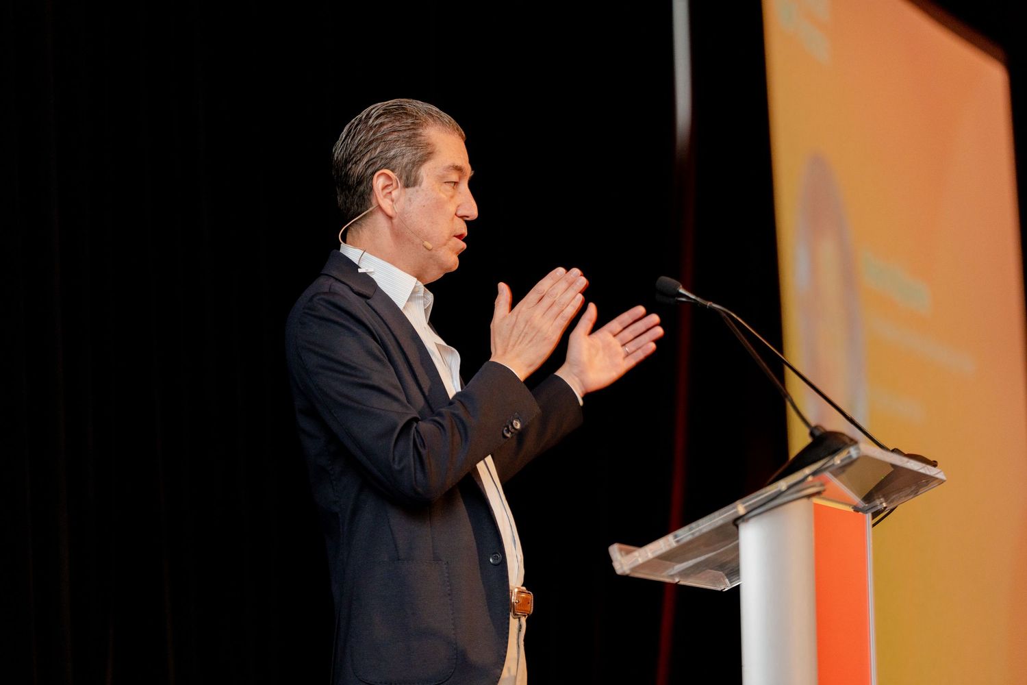 Speaker presenting at a podium during a professional business conference.