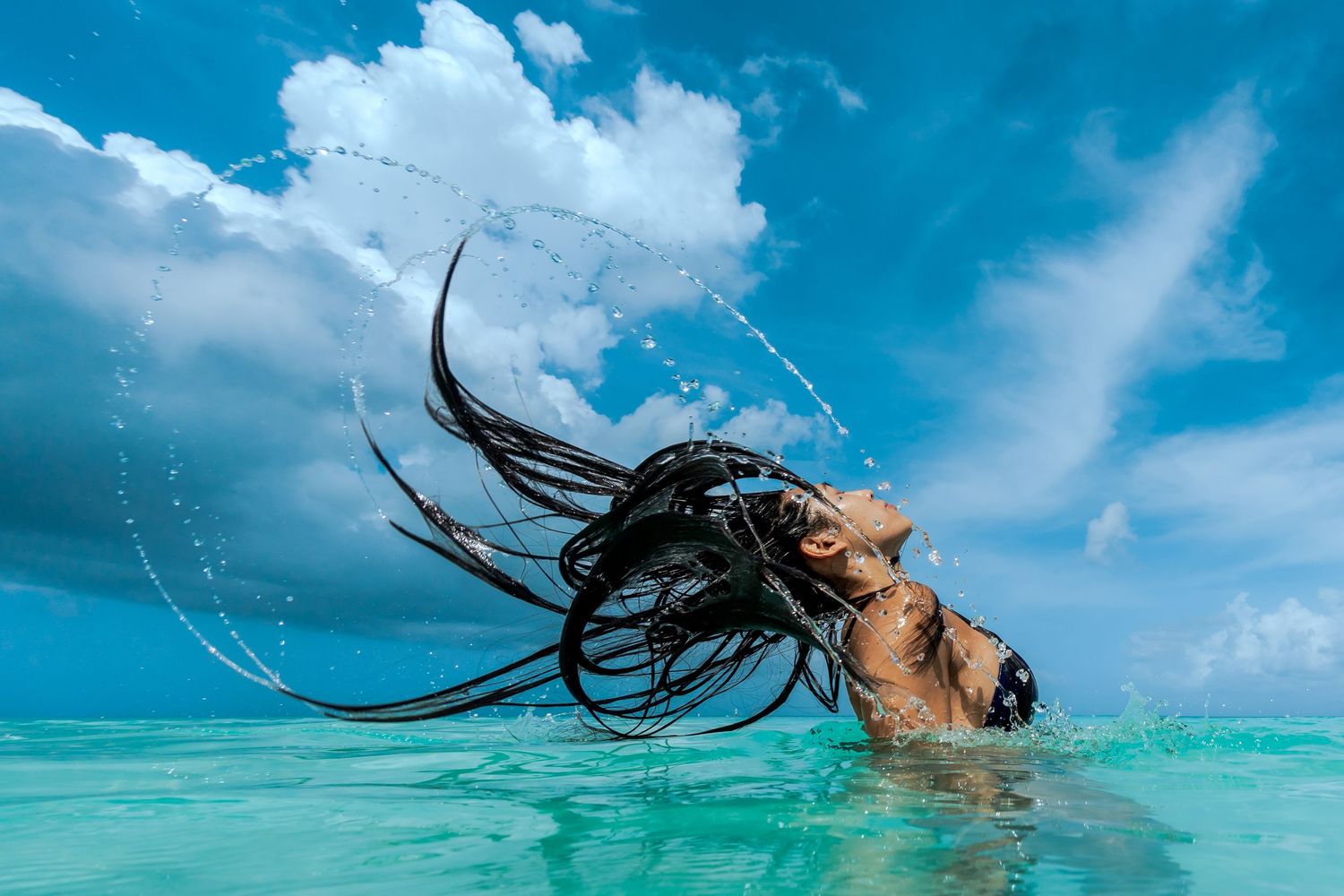 Underwater view of someone swimming in clear blue ocean water.