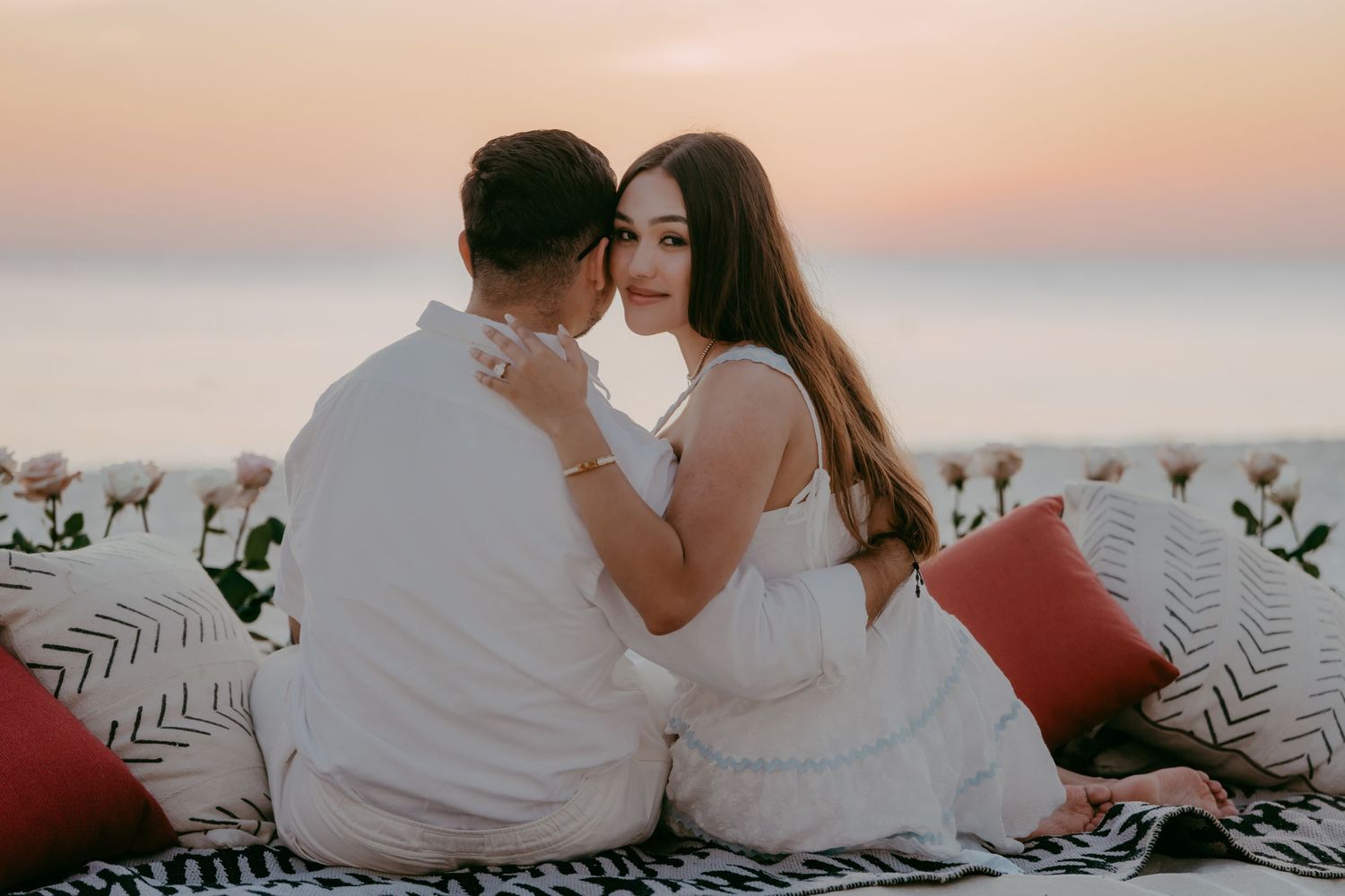 Intimate beach scene with couple cuddling at dusk.