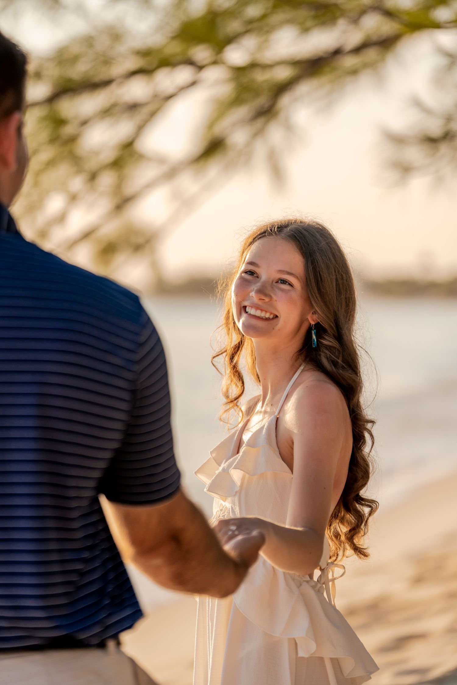 Romantic beach proposal photoshoot during golden hour with joyful expressions.