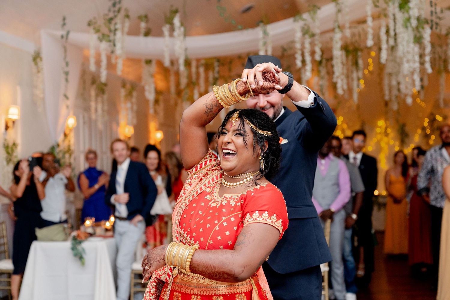 Wedding reception features couple dancing under elegant floral ceiling decorations.