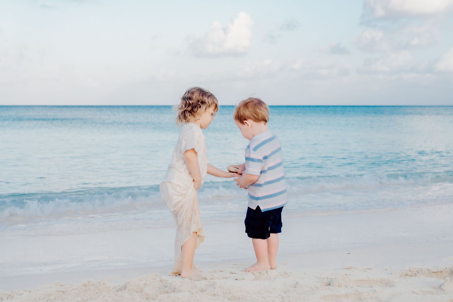 A group enjoying a sunset photoshoot on a pristine white sand beach with turquoise waters in the background.