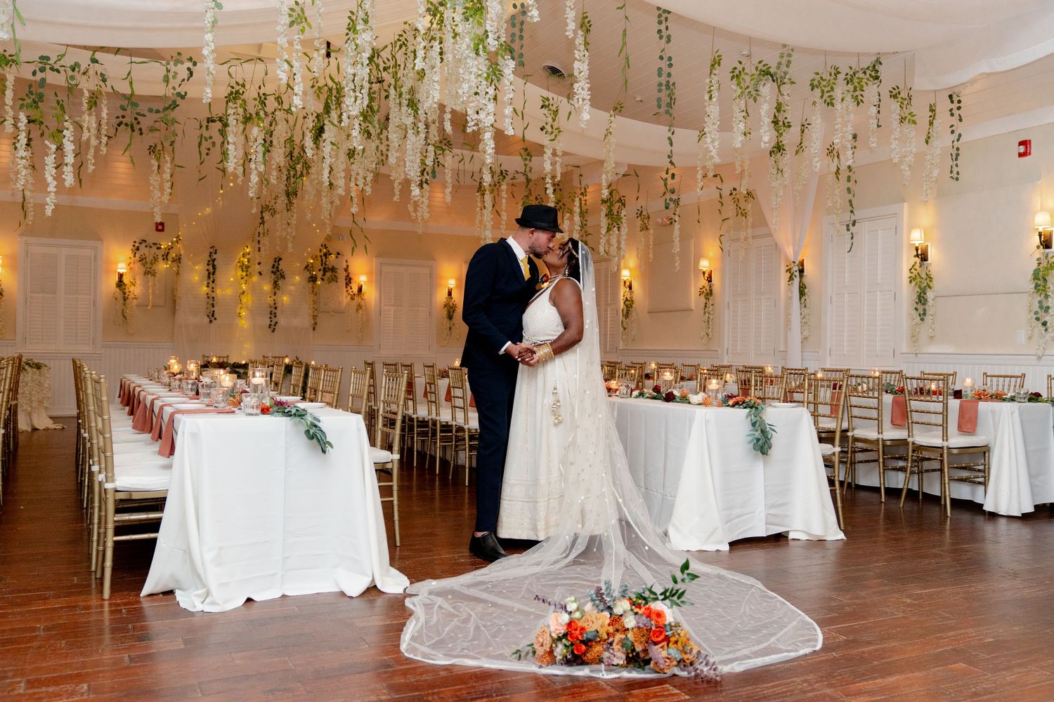 Elegant wedding reception venue decorated with hanging floral arrangements and white linens.