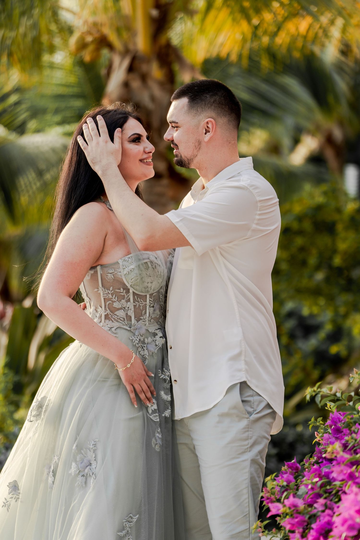Romantic couple embracing near vibrant pink flowers in a garden setting.