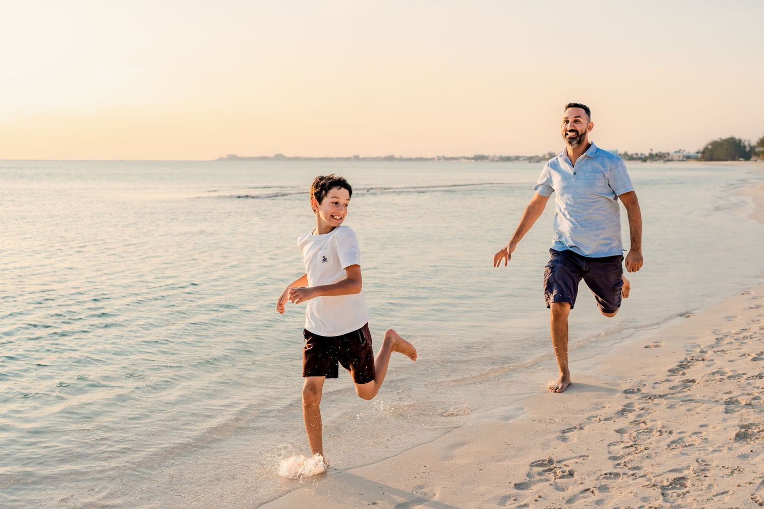 Active beach scene with people running and playing in the sand at golden hour.