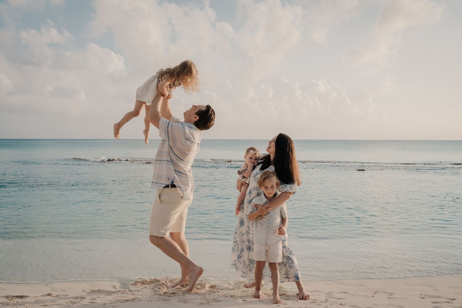 Carefree moments captured on a pristine beach with soft pink clouds and calm waters.