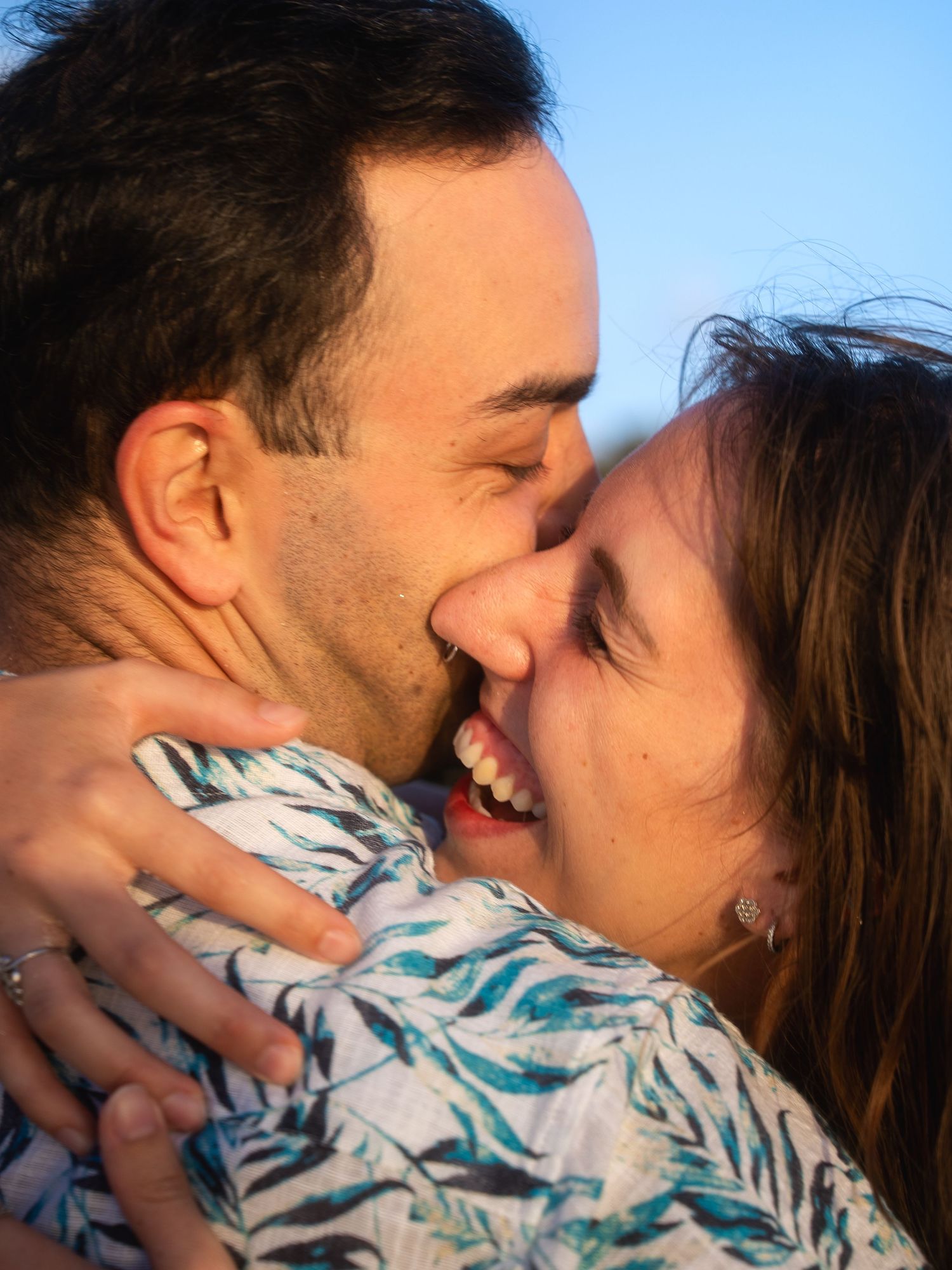 Happy couple sharing a joyful embrace and laugh outdoors in warm golden light.