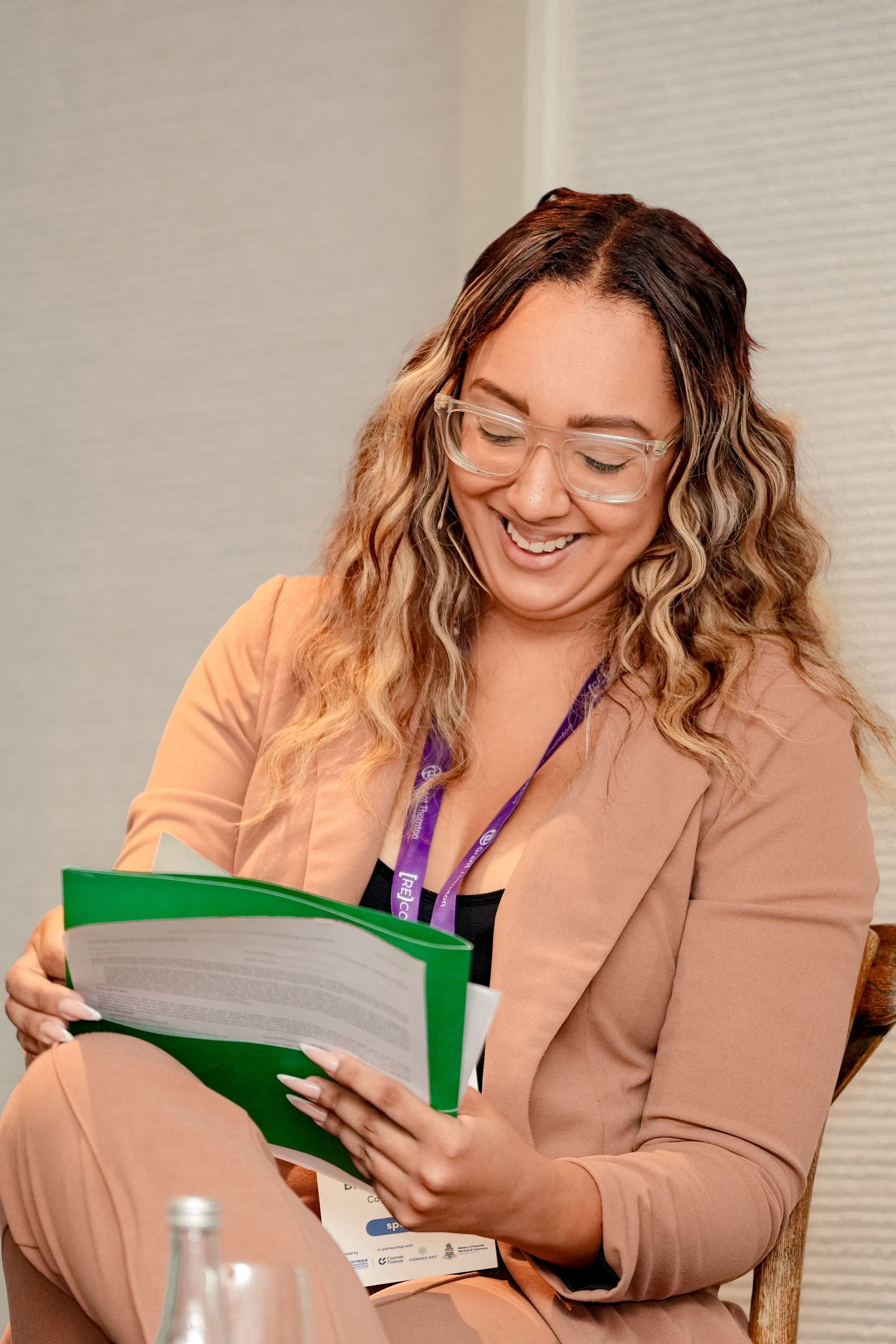 Professional reviewing documents in a green folder during a business meeting.