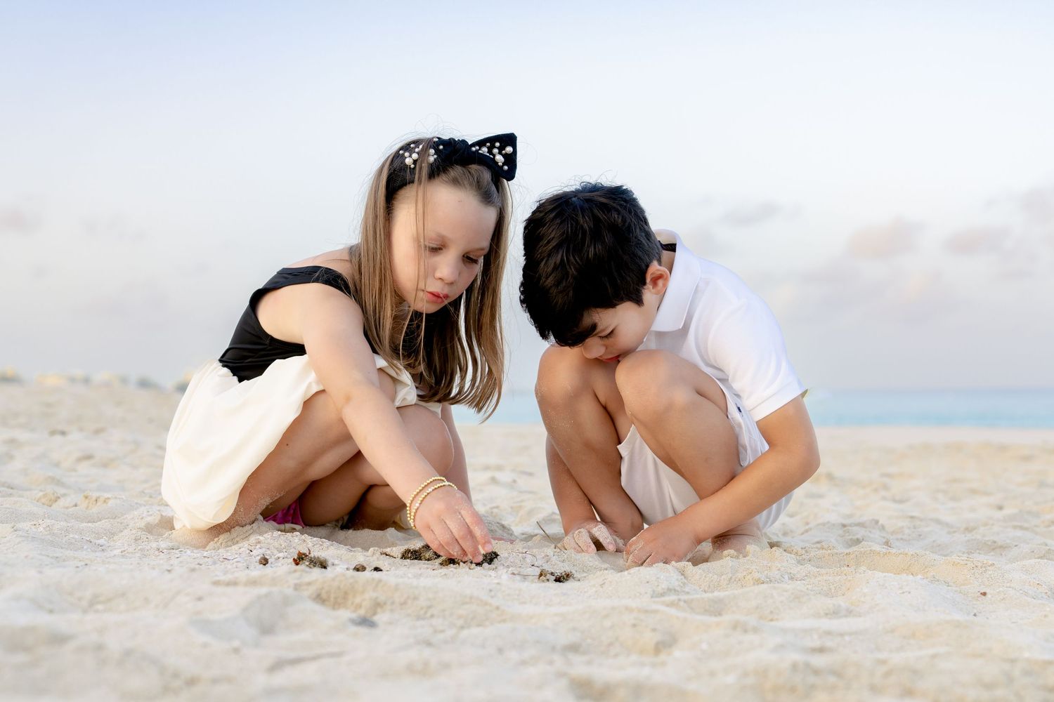 People lying down and playing in the soft sand at the beach.