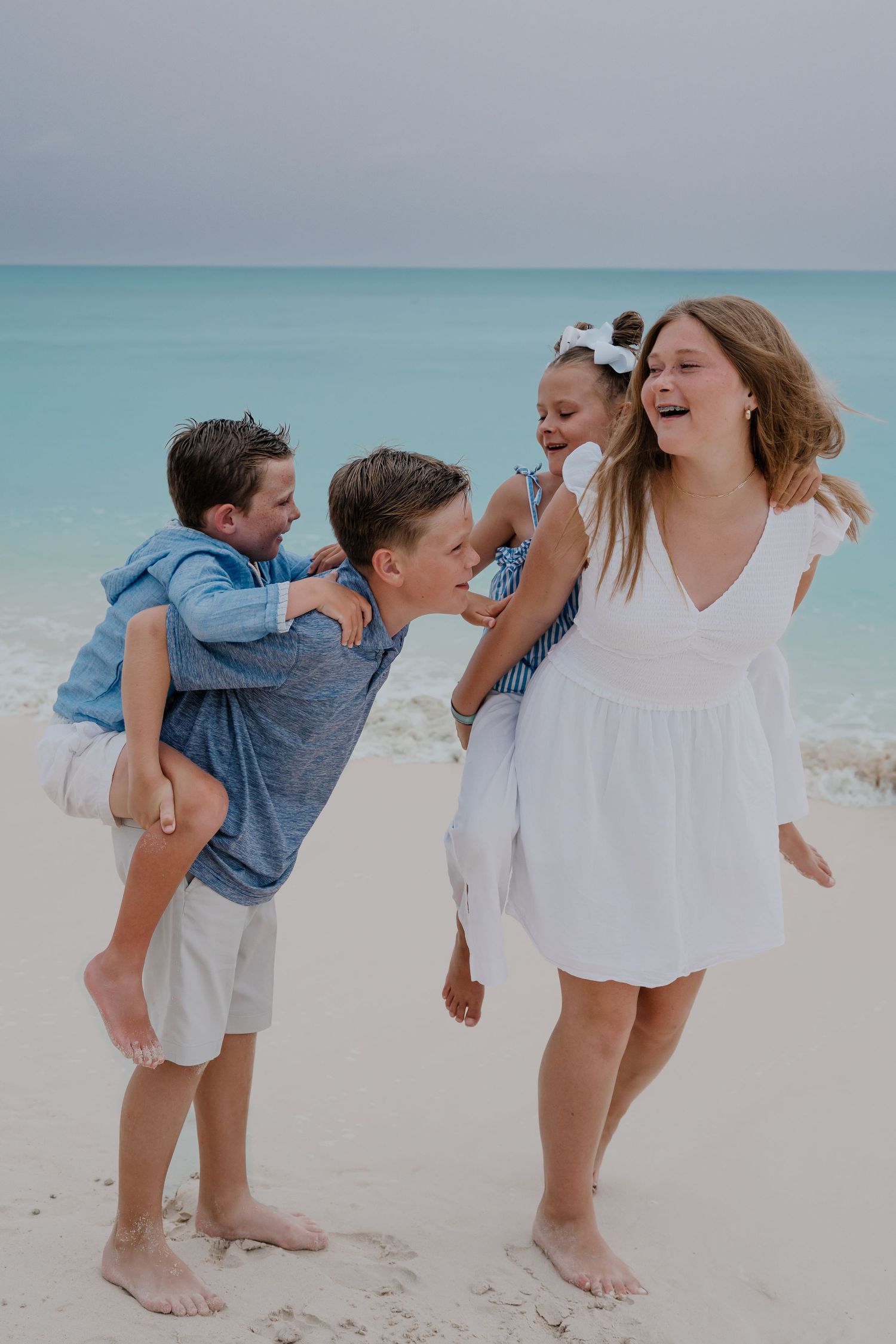 Candid moments of family members playing and laughing together on a white sandy beach.