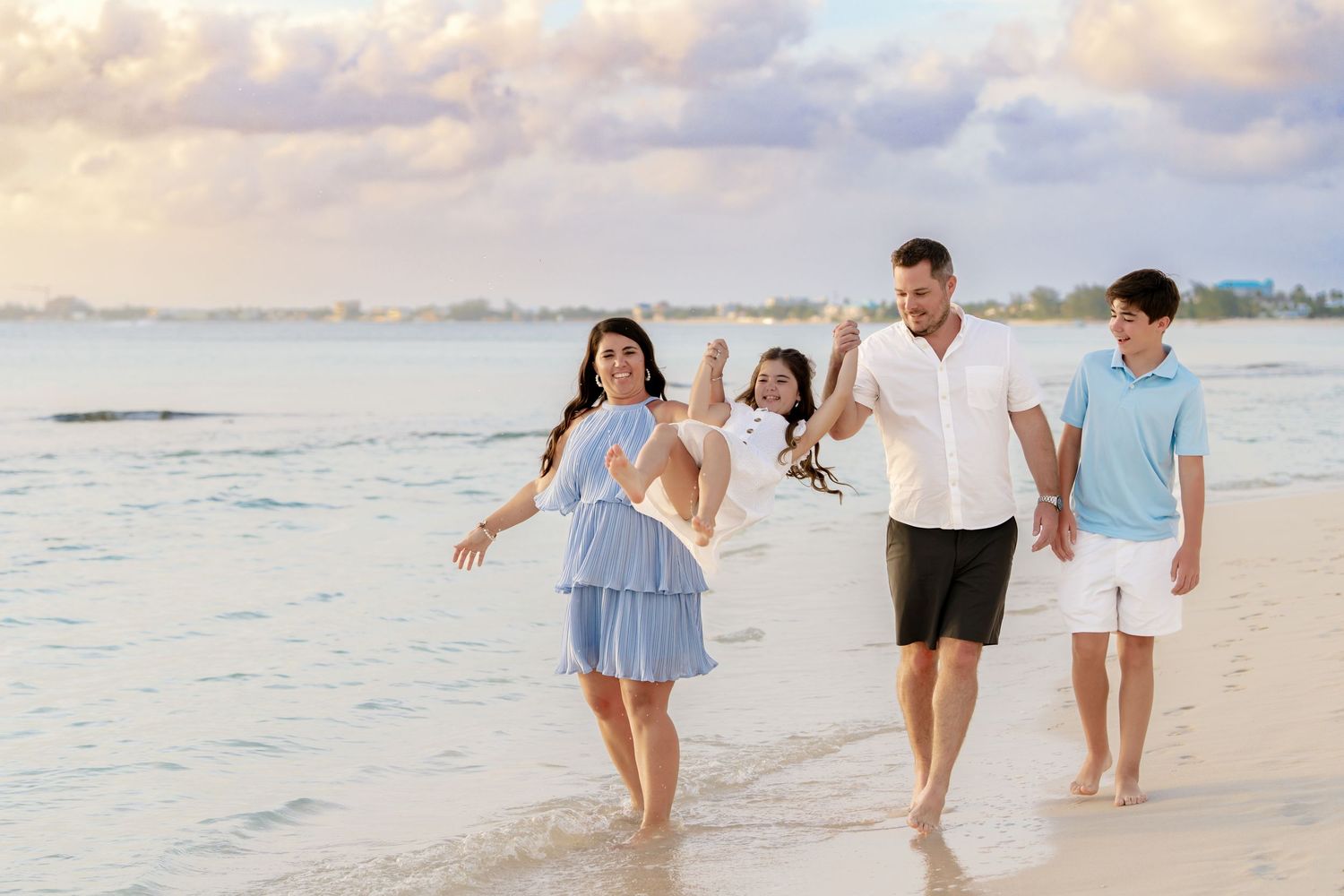 Group enjoying a casual stroll along the shoreline during golden hour at the beach.
