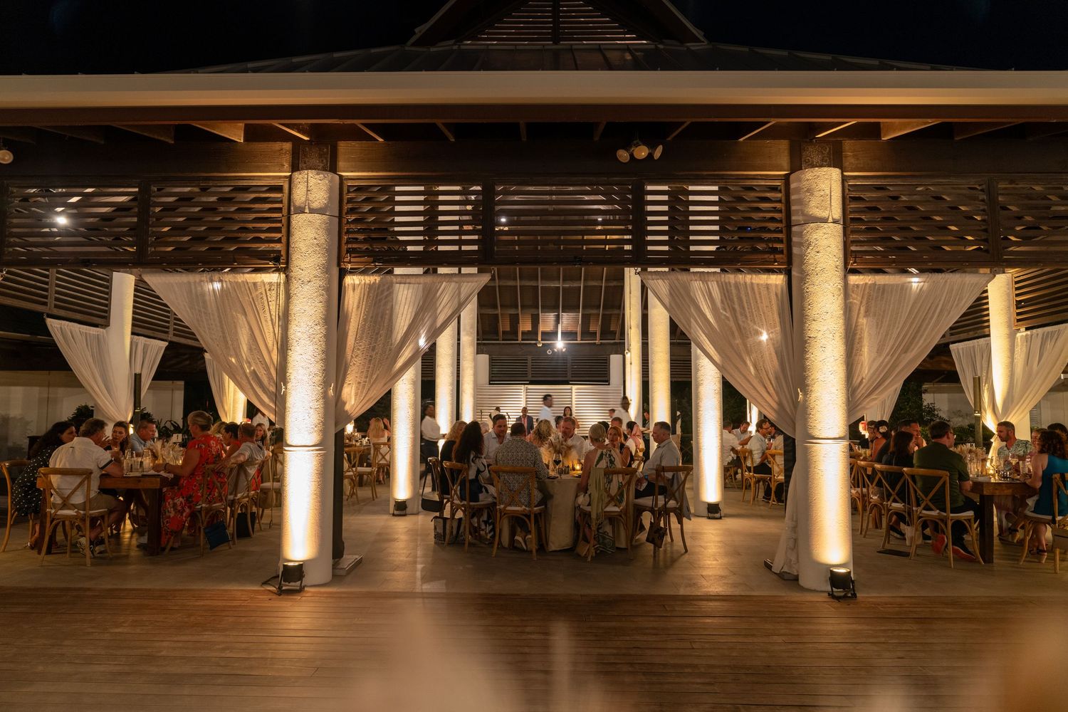 Large open-air reception venue with pillars and ambient lighting for an evening event.