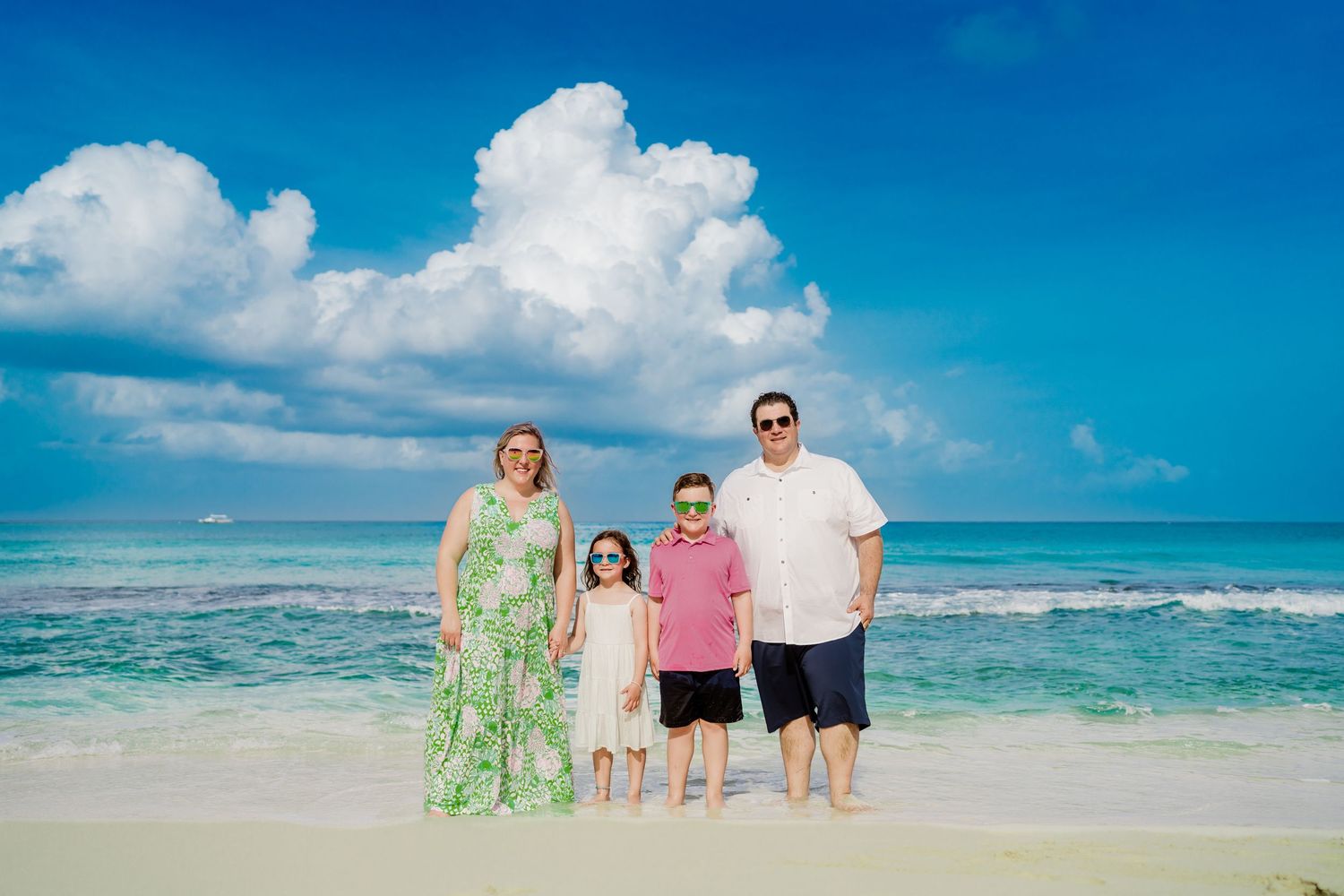 Family portrait session on a stunning beach with turquoise water and fluffy white clouds.
