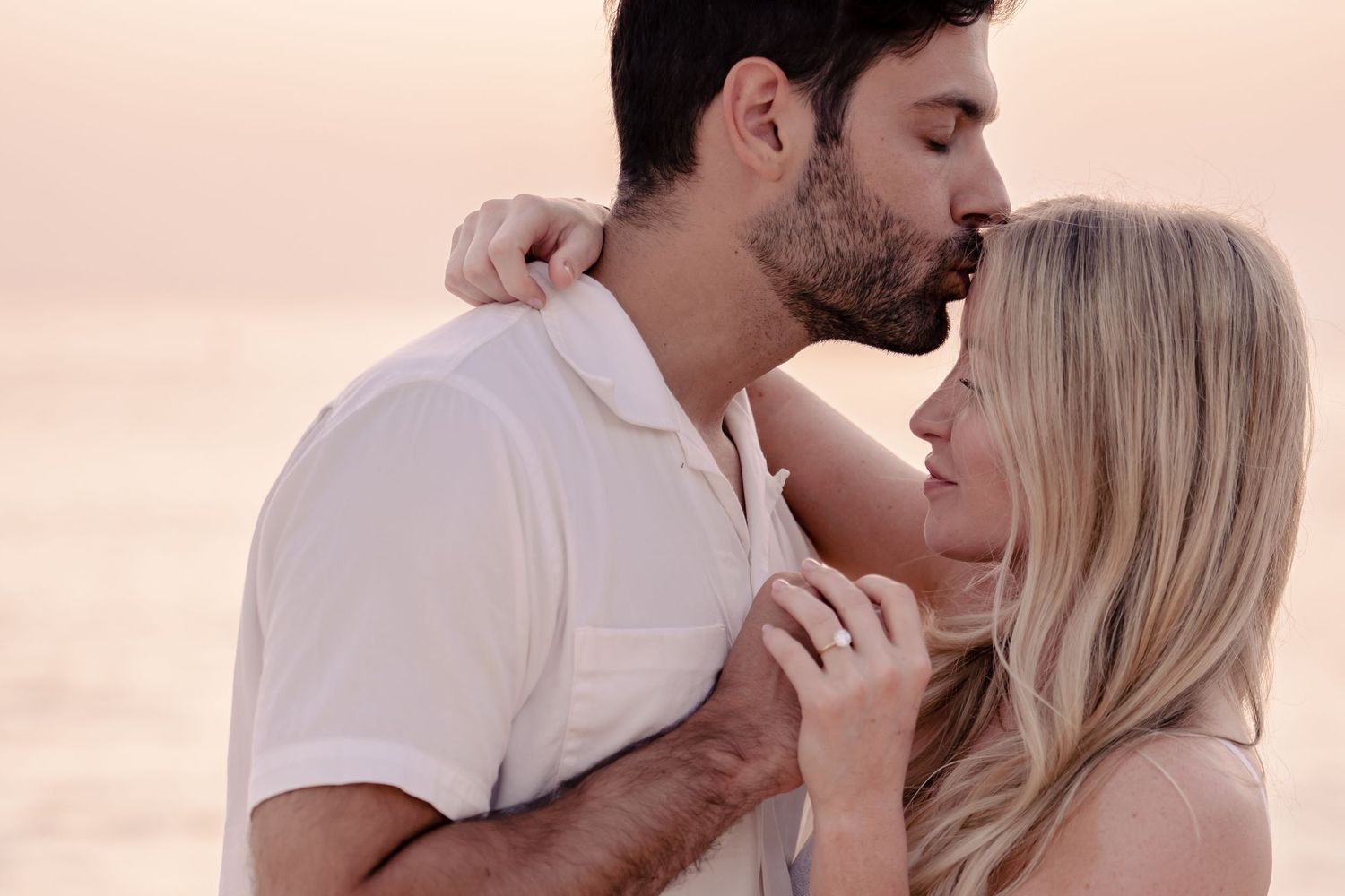 Romantic couple shares intimate moments on beach during golden hour sunset photography session.