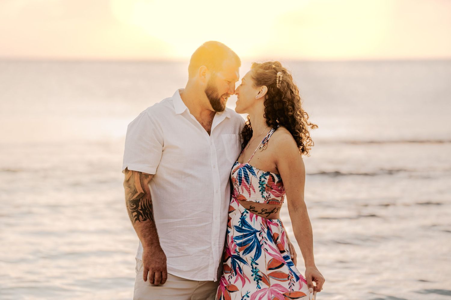 Romantic beach portraits during golden hour with ocean waves in background.