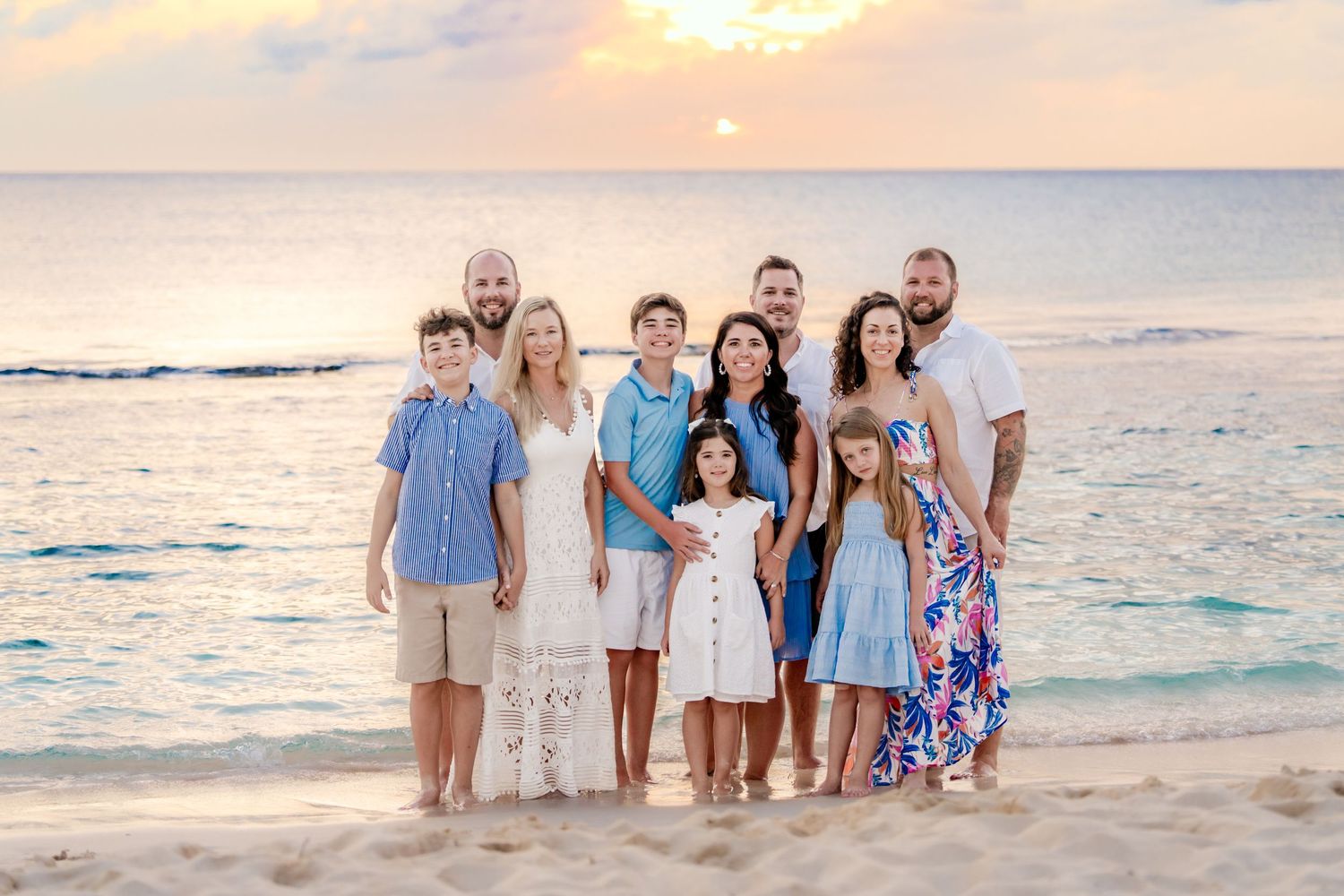 Family group walking along a pristine beach at sunset wearing coordinated blue and white outfits.