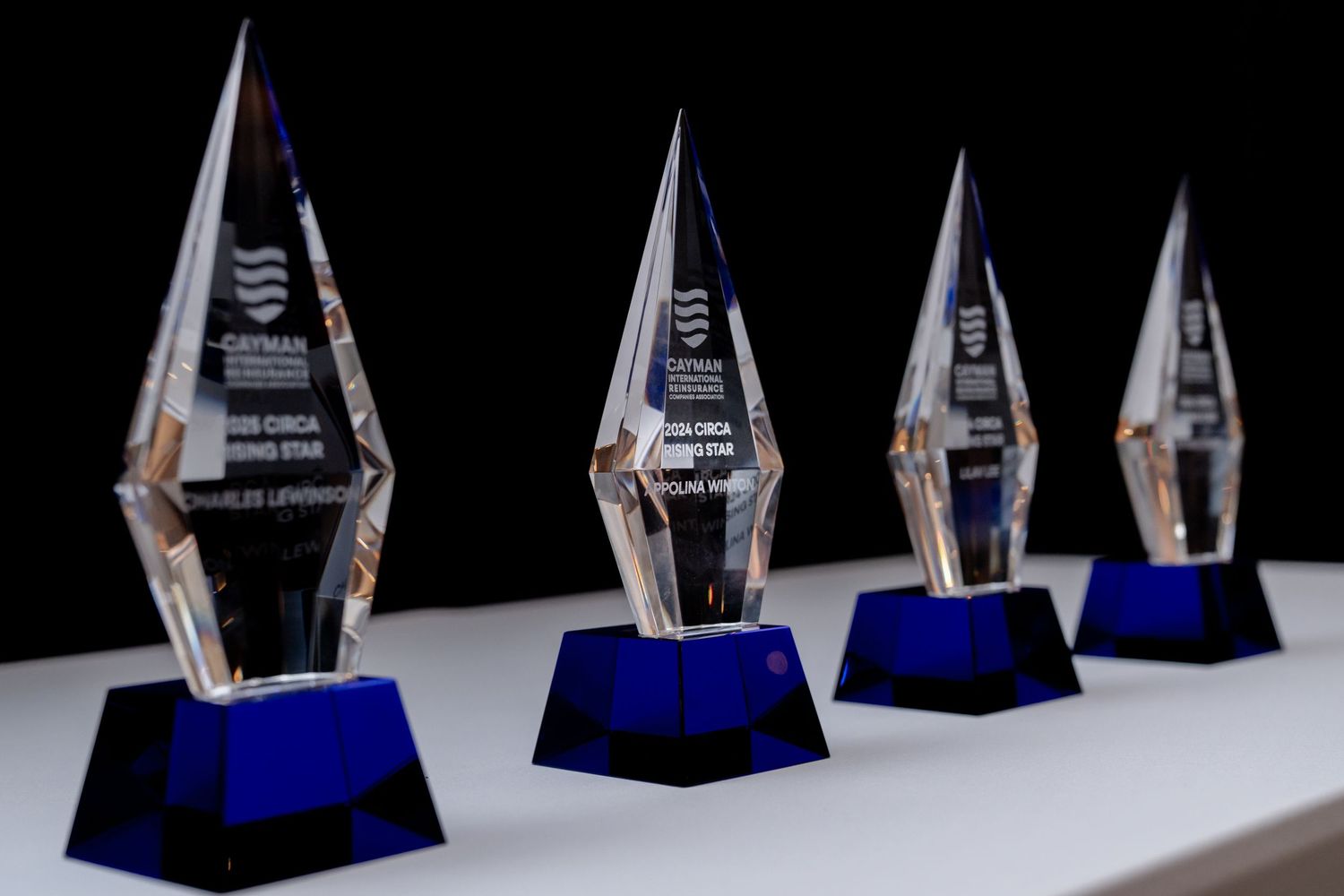 Row of crystal trophy awards displayed on blue bases against dark background.