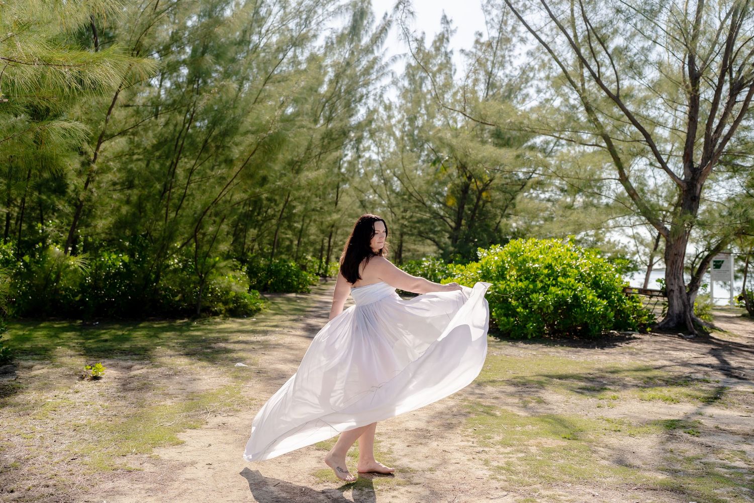 Pink fabric flows gracefully along a beach path lined with tropical trees and greenery.