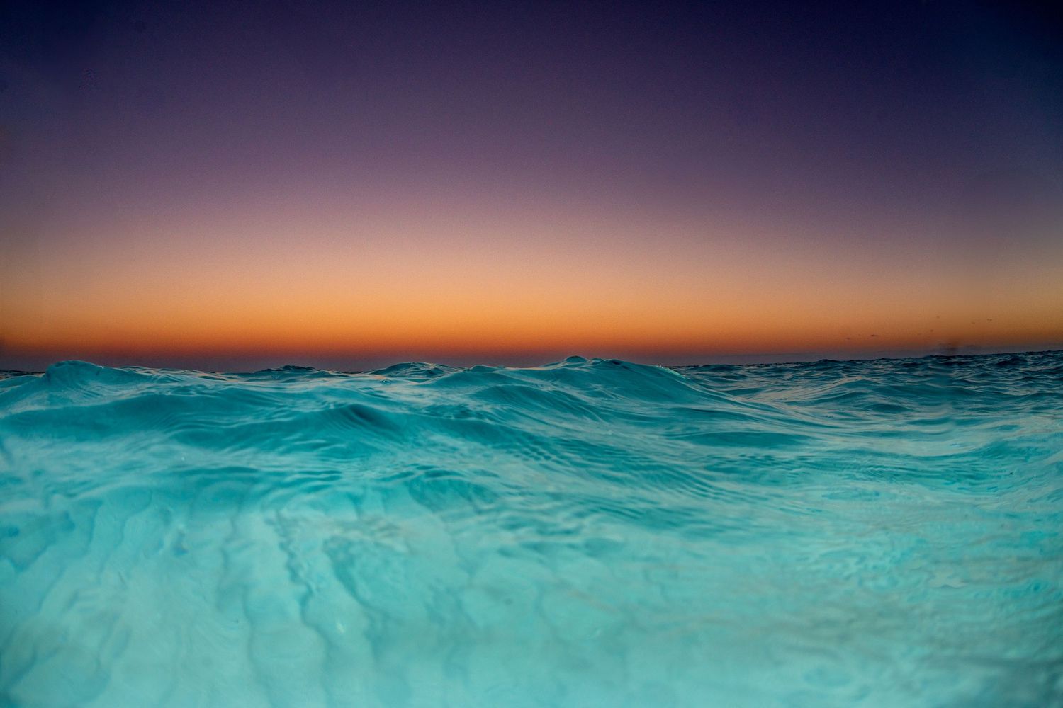 Dramatic ocean sunset with split view showing waves and colorful sky.