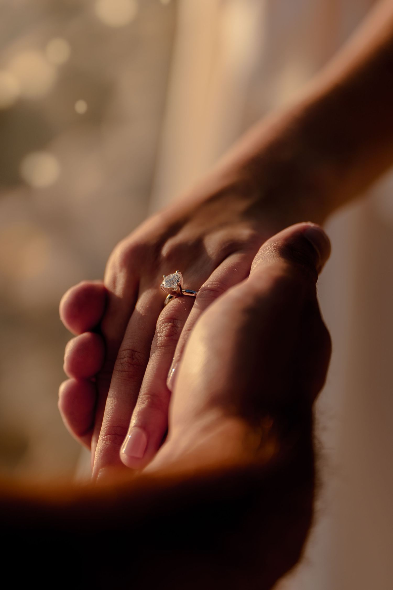 Close-up shots of hands with engagement ring in warm lighting showing sparkly diamond details.