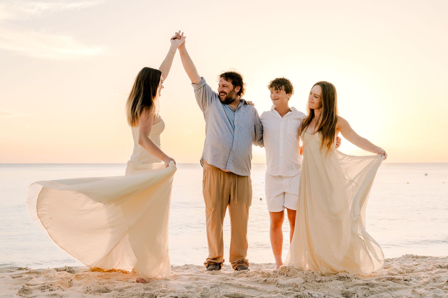 People in light clothing create joyful poses on a beach during golden hour.