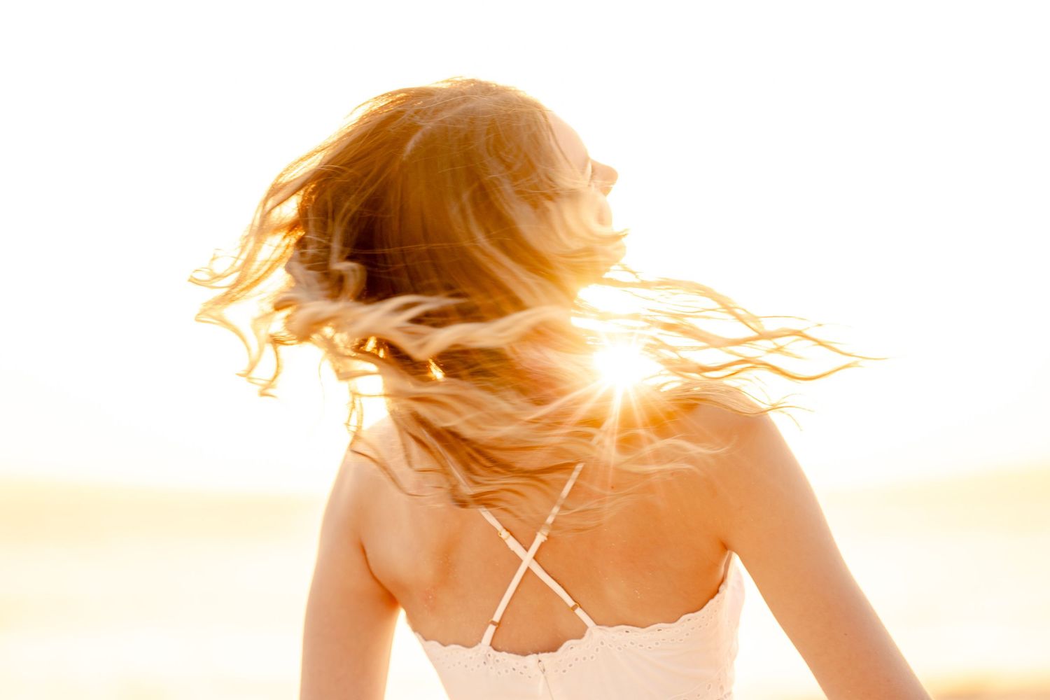 Silhouette of person against golden sunset sky at beach.