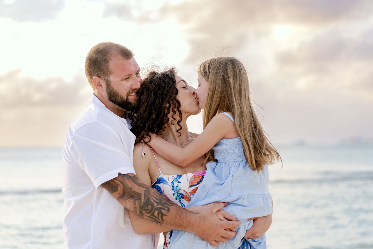 Romantic couples embracing on sandy beach during sunset with ocean waves in background.