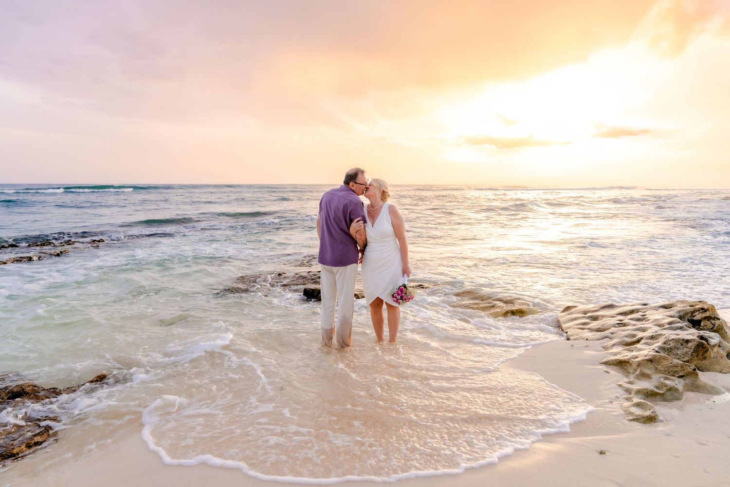 Romantic beach sunset with waves crashing on the shore and silhouettes walking along the water's edge.