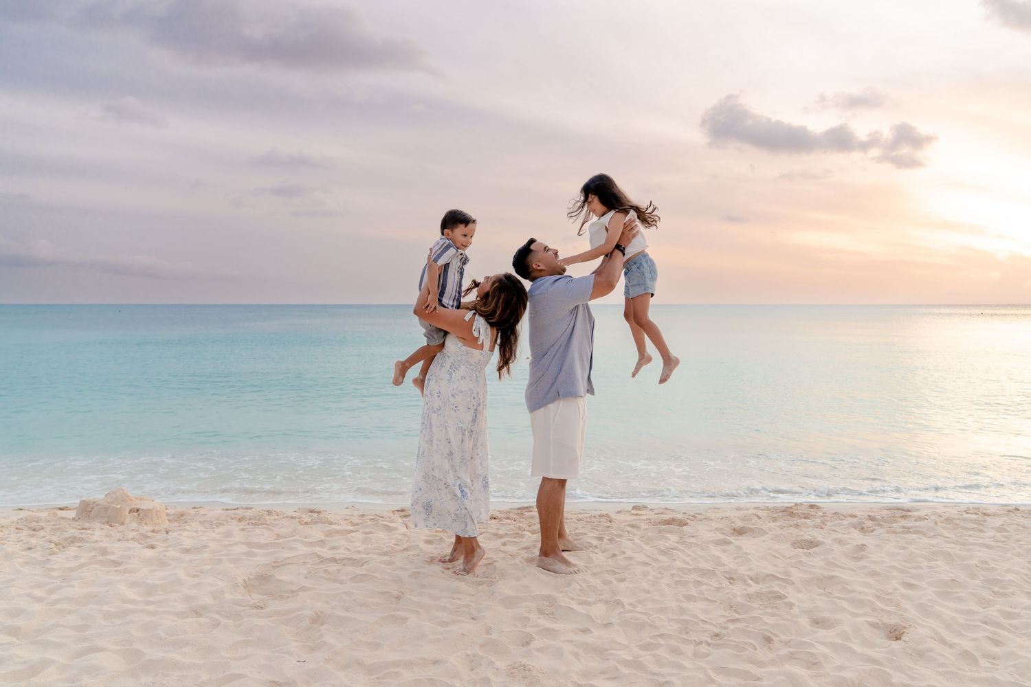 A group enjoys a sunset walk along a pristine white sand beach with turquoise waters in the background.