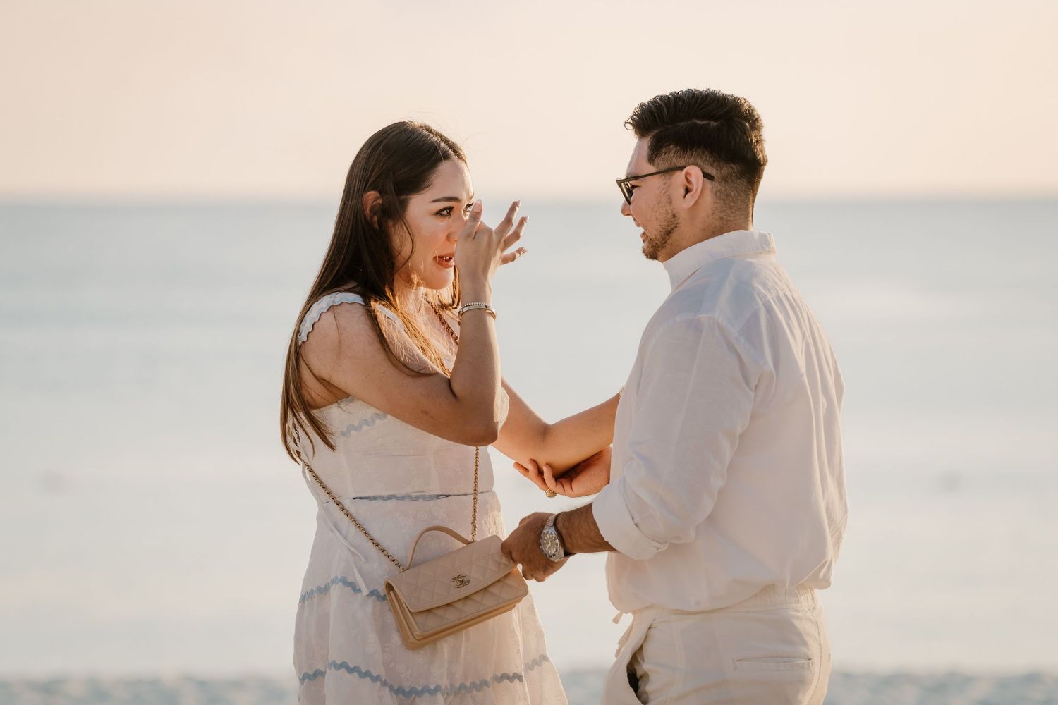 A couple shares an emotional moment on the beach during golden hour.