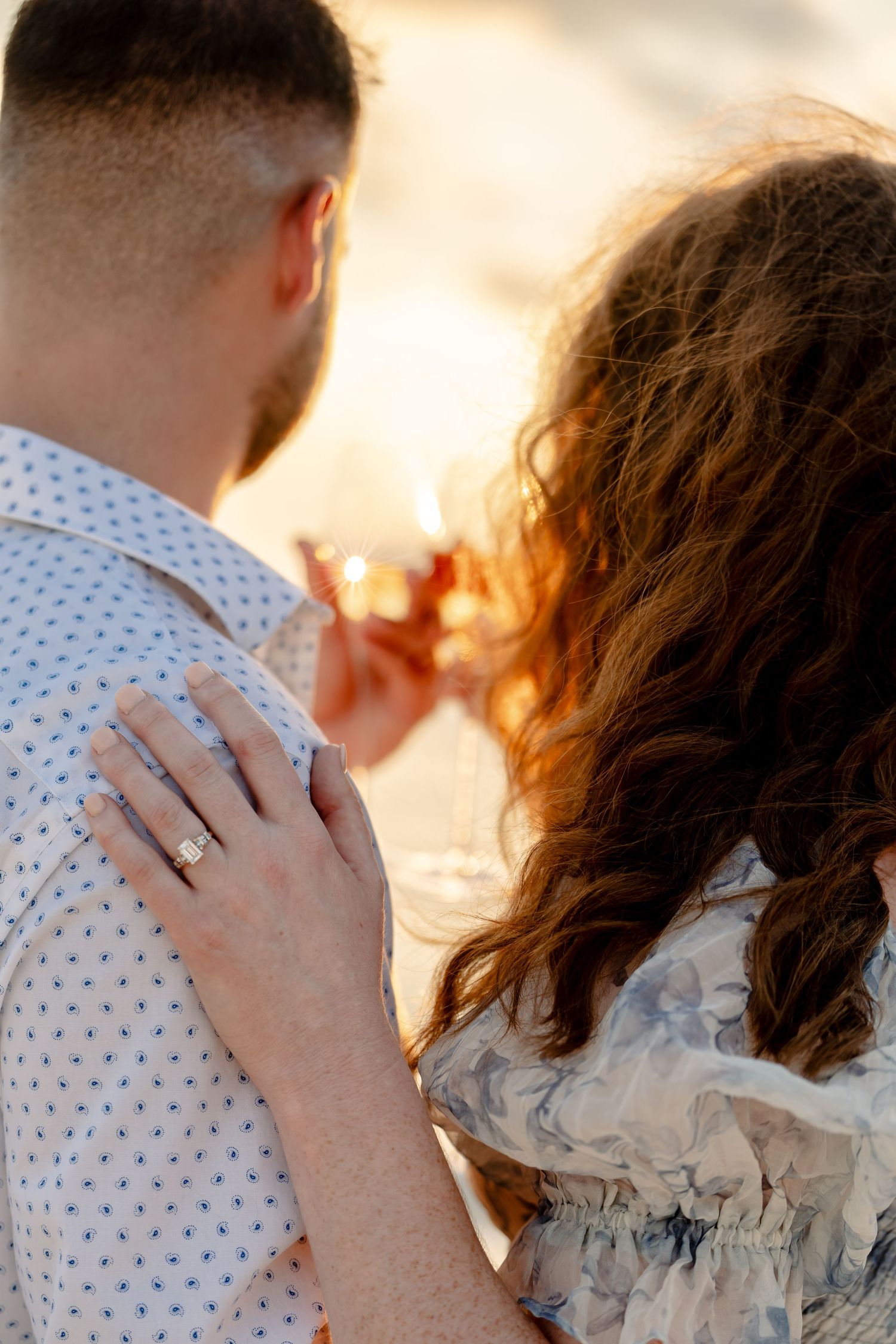 Close-up shot showing an engagement ring during a sunset beach proposal.