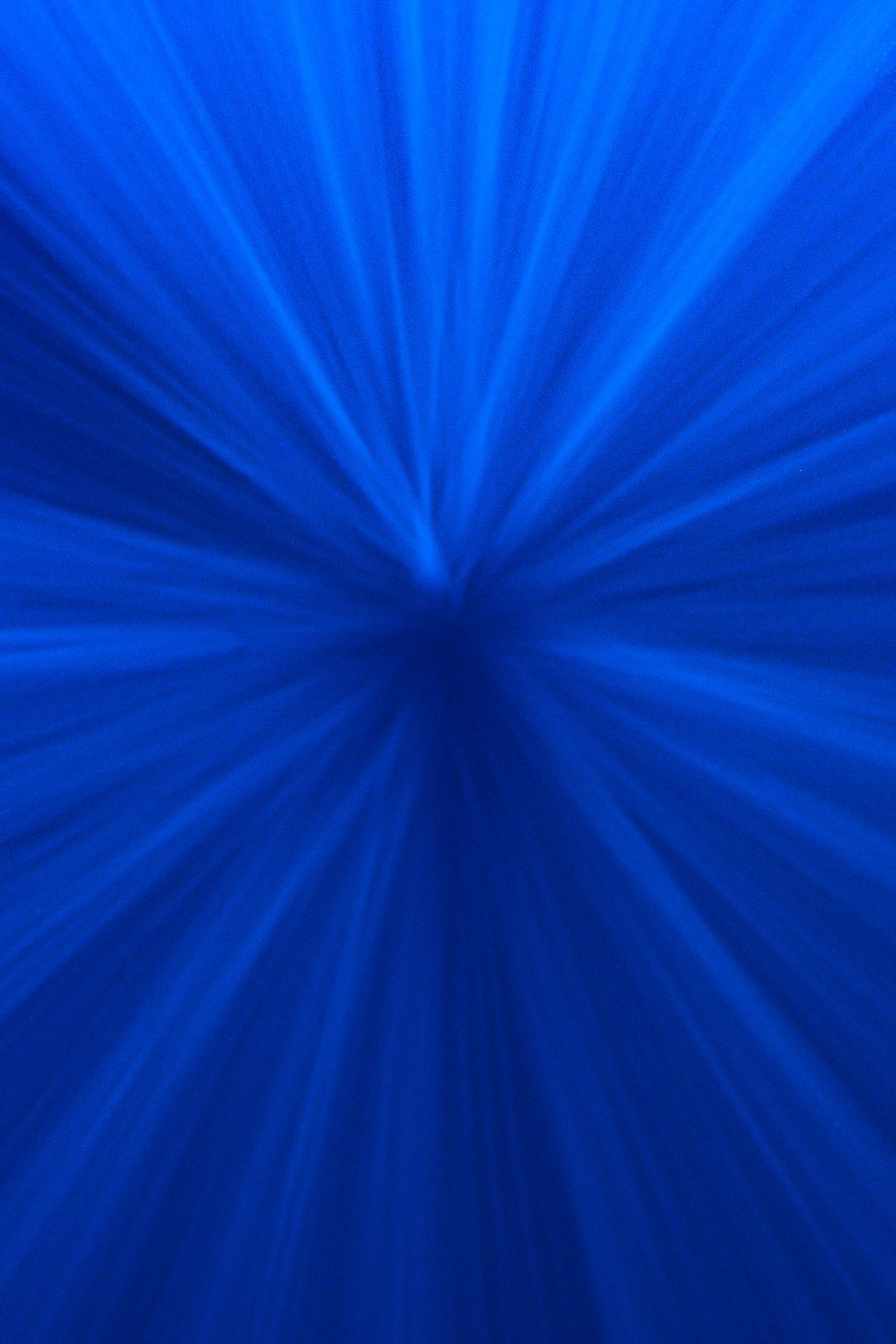 Abstract blue radial light burst pattern creating a dynamic underwater effect.