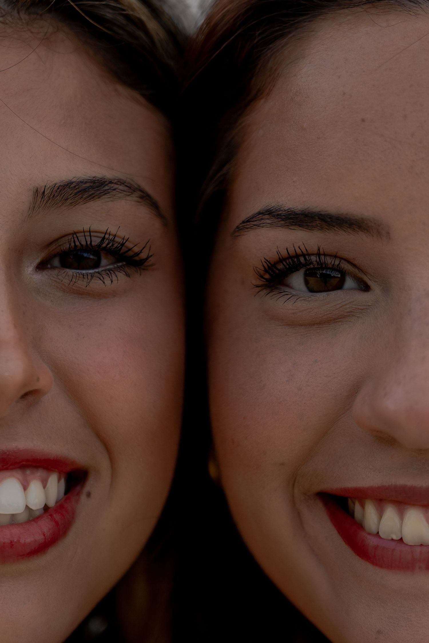 Close up of smiling faces with red lipstick in dark lighting.