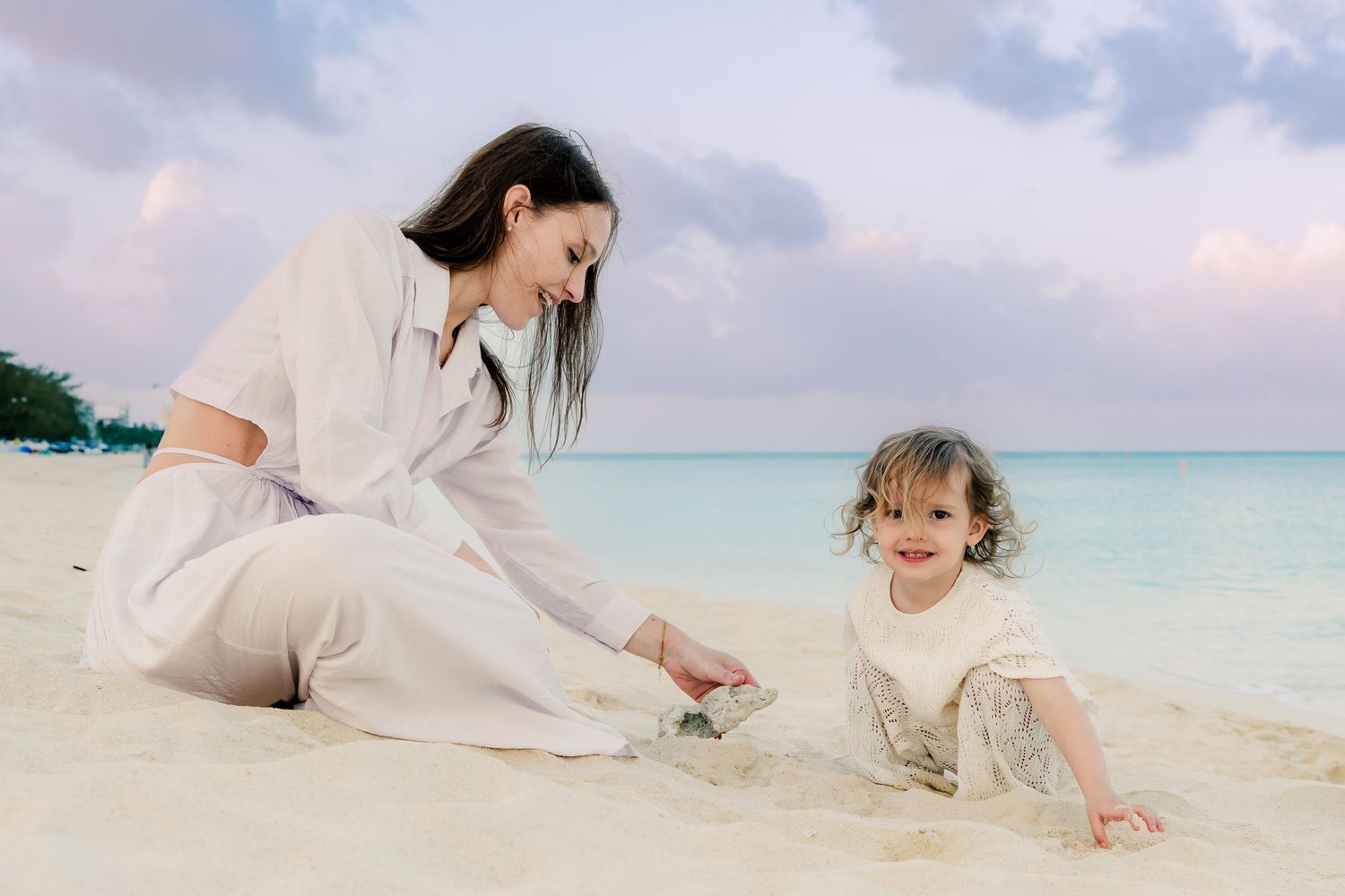 Family playing in the sand during a relaxed beach photo session at dusk.