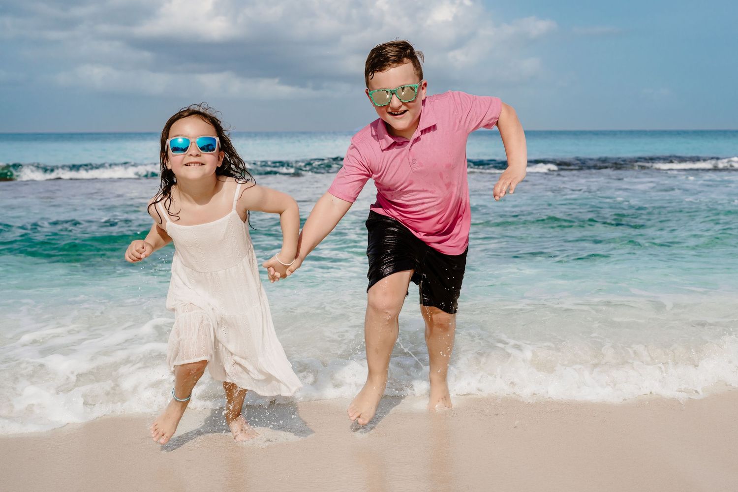 Playful beach photography session with people jumping and splashing in the surf.