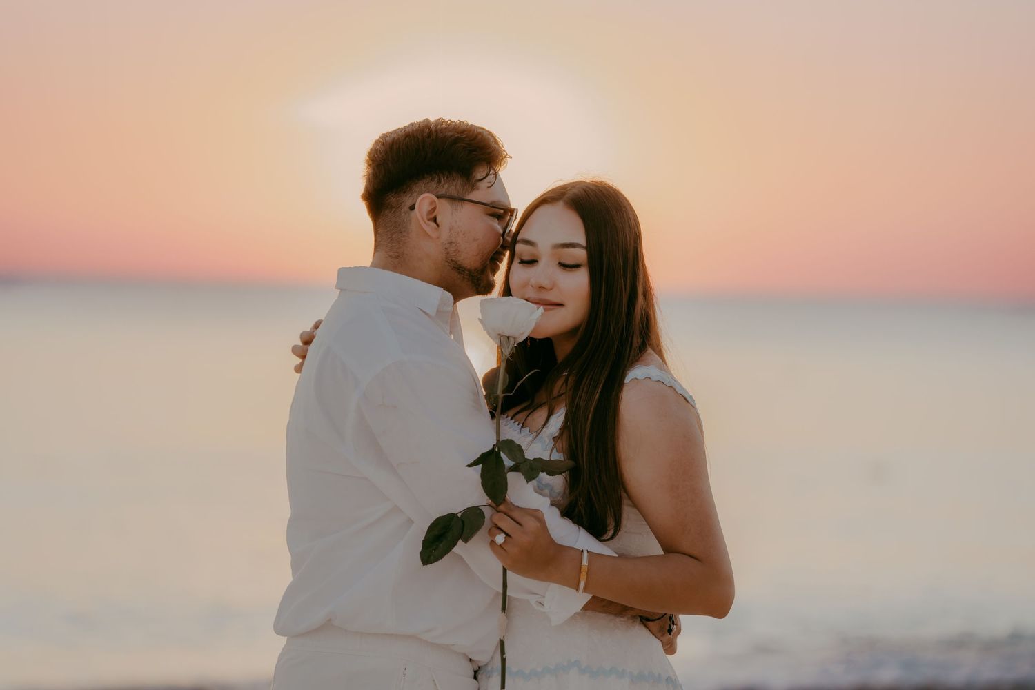 A romantic sunset beach scene with two people sharing an intimate moment.