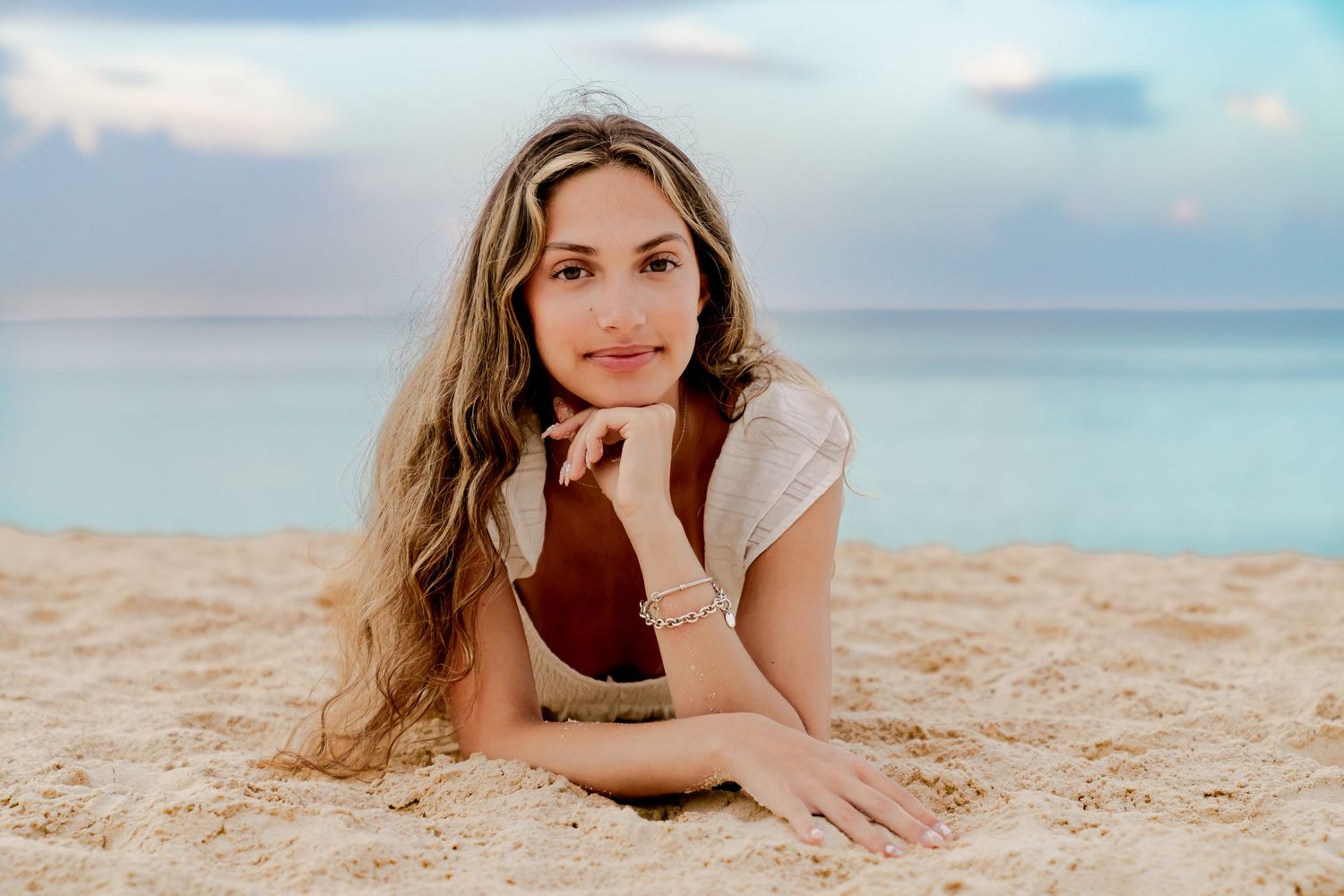 A relaxed beach portrait showing someone lying in soft sand with ocean waves in the background.