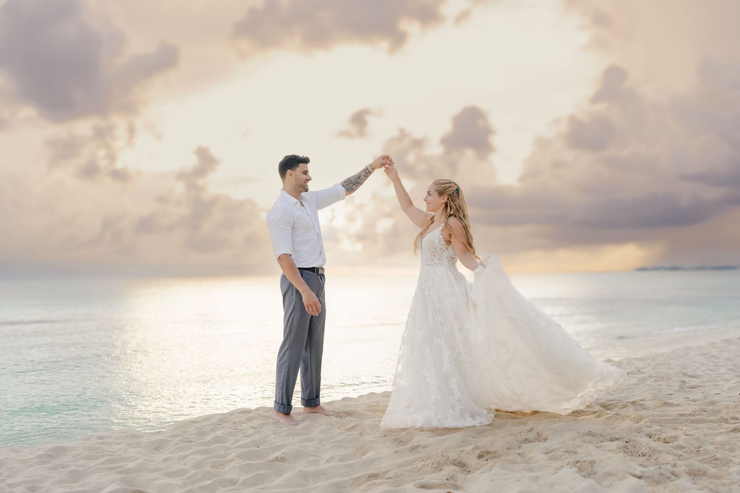 A romantic beach photoshoot featuring a couple dancing together against a sunset sky.